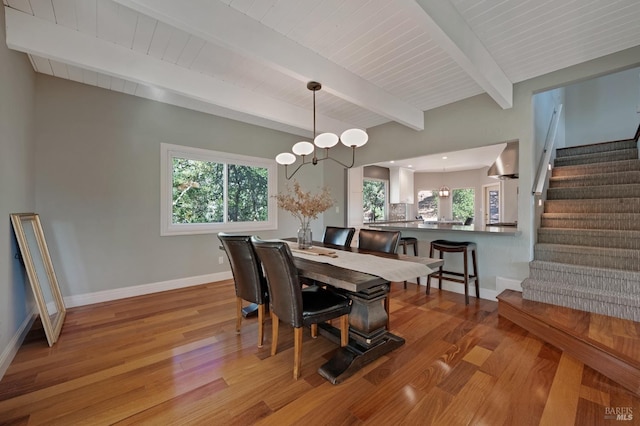 dining room with beam ceiling, light hardwood / wood-style floors, and wooden ceiling