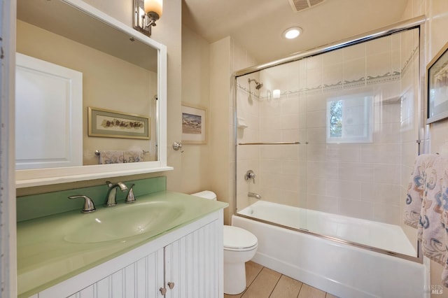 full bathroom featuring vanity, toilet, and bath / shower combo with glass door