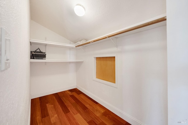 walk in closet with wood-type flooring and vaulted ceiling