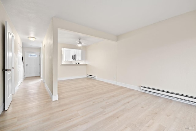 spare room featuring ceiling fan, light wood-type flooring, and a baseboard radiator