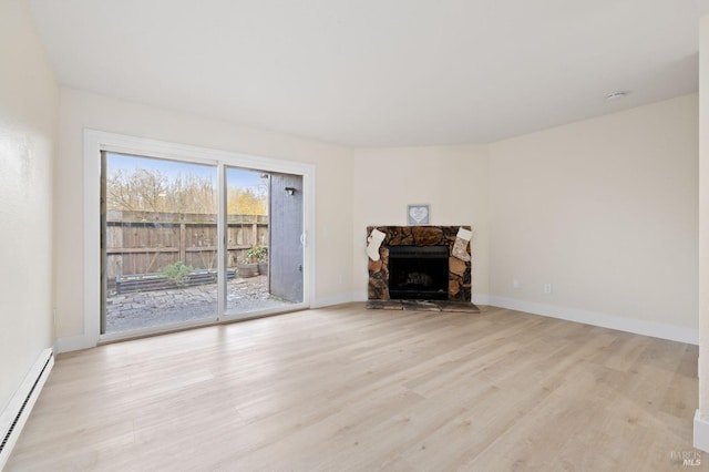 unfurnished living room featuring light hardwood / wood-style floors, baseboard heating, and a stone fireplace