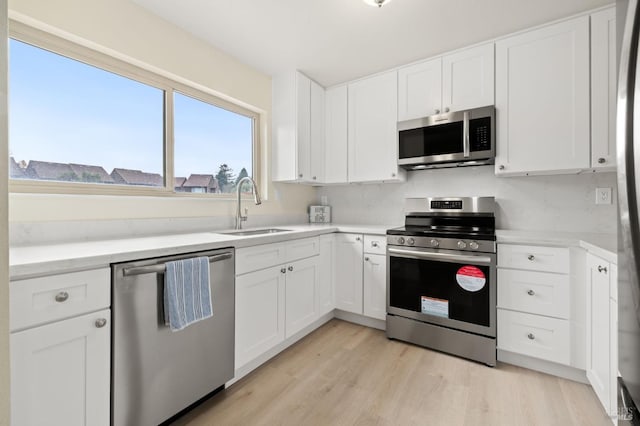 kitchen featuring appliances with stainless steel finishes, white cabinetry, plenty of natural light, and sink