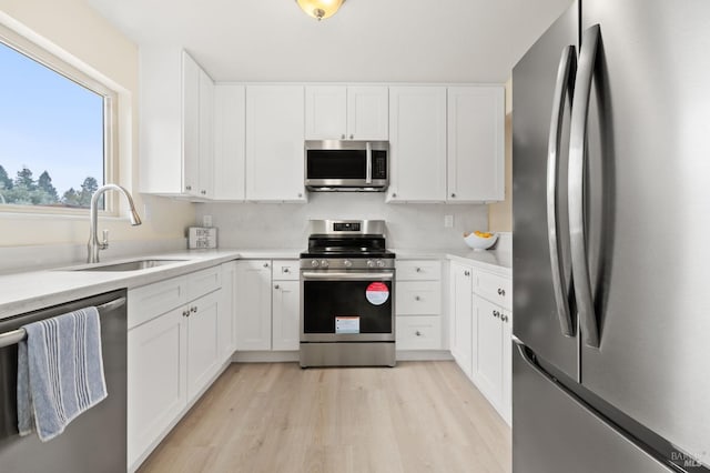 kitchen featuring stainless steel appliances, white cabinetry, and sink