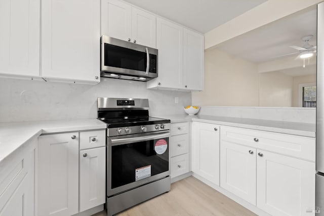 kitchen with stainless steel appliances, white cabinetry, ceiling fan, and light wood-type flooring