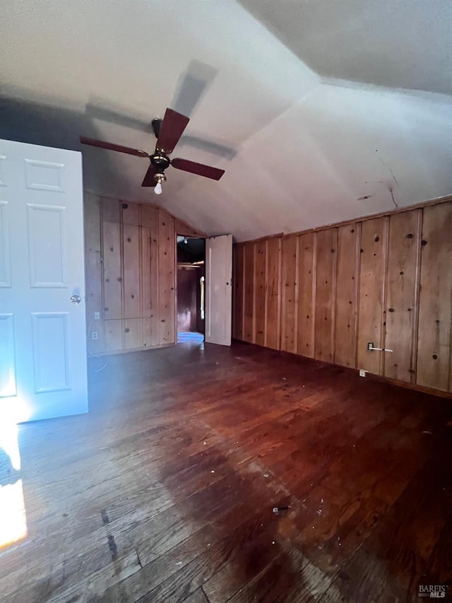 additional living space featuring vaulted ceiling, dark hardwood / wood-style floors, and wood walls