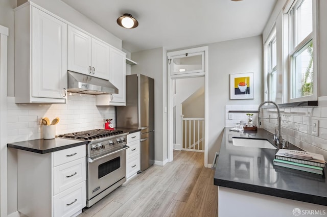 kitchen with appliances with stainless steel finishes, light hardwood / wood-style flooring, white cabinetry, and sink