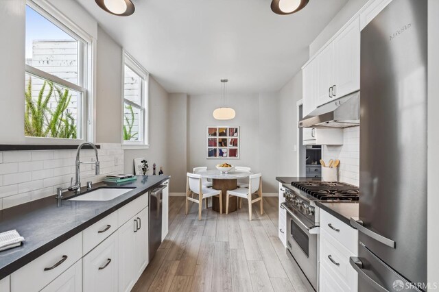 kitchen featuring appliances with stainless steel finishes, decorative light fixtures, white cabinetry, decorative backsplash, and sink