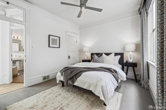 carpeted bedroom featuring ceiling fan, ornamental molding, and ensuite bath