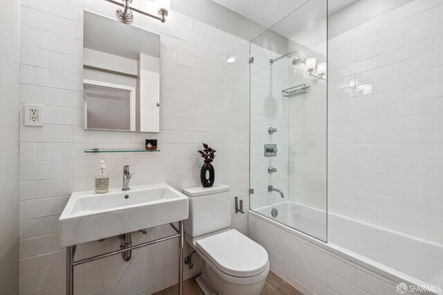 full bathroom featuring sink, tile walls, toilet, and tiled shower / bath combo