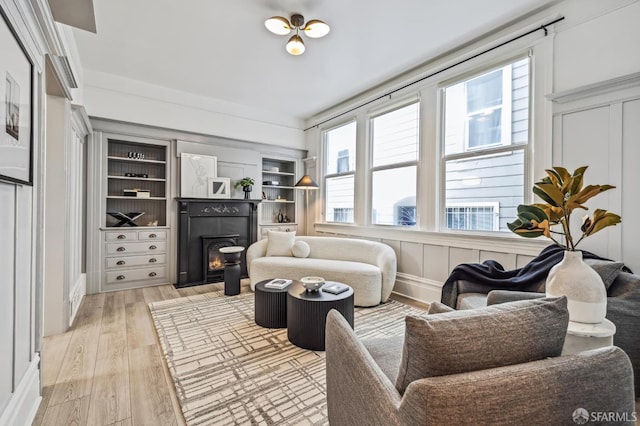 living room featuring built in features and light hardwood / wood-style flooring