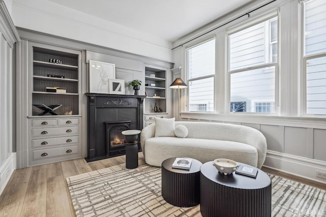 living area with light hardwood / wood-style floors and built in shelves