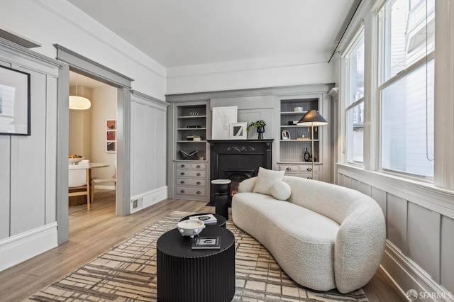 sitting room featuring built in features, a wealth of natural light, and hardwood / wood-style floors