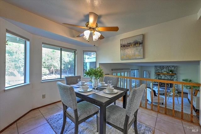 dining area with ceiling fan, a fireplace, and light tile patterned floors