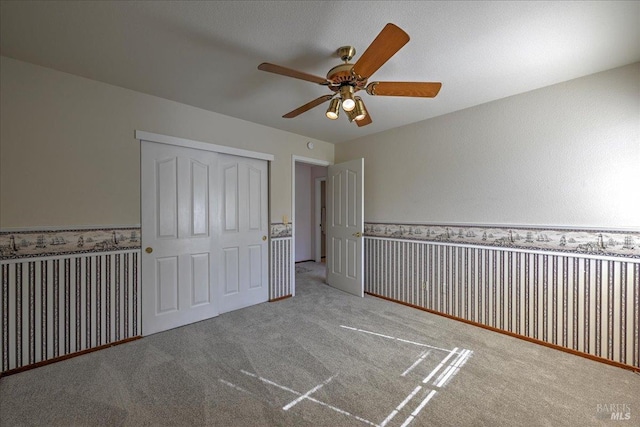 unfurnished bedroom featuring light carpet, a closet, and ceiling fan