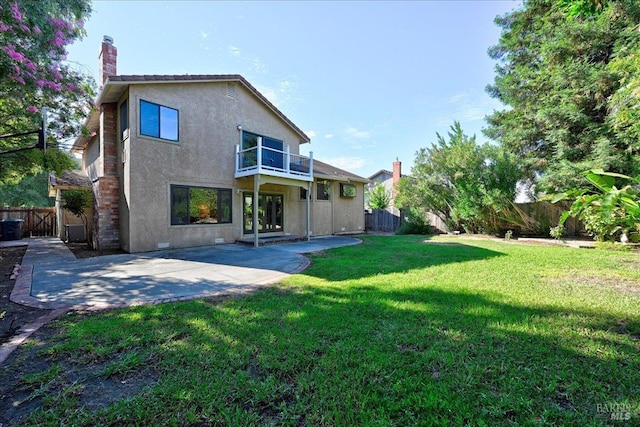 rear view of property featuring a patio, a balcony, and a lawn