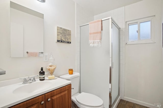 bathroom with a shower with door, vanity, hardwood / wood-style floors, and toilet