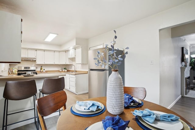 kitchen with sink, light hardwood / wood-style flooring, kitchen peninsula, white cabinets, and appliances with stainless steel finishes