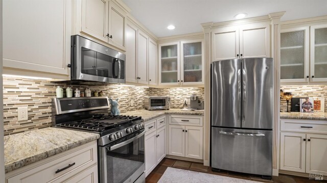 kitchen featuring tasteful backsplash, light stone countertops, and appliances with stainless steel finishes