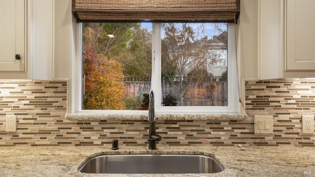 details with light stone countertops, tasteful backsplash, white cabinets, and a sink