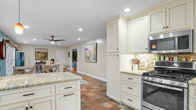 kitchen with open floor plan, appliances with stainless steel finishes, light stone countertops, tasteful backsplash, and decorative light fixtures