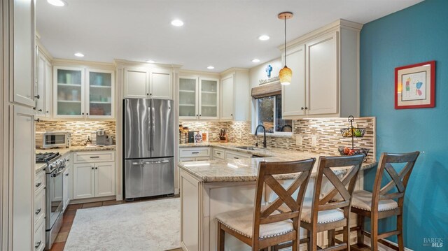 kitchen with pendant lighting, sink, stainless steel appliances, a kitchen breakfast bar, and kitchen peninsula