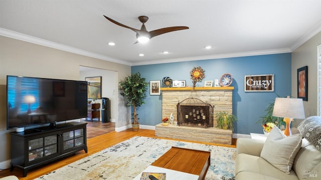 living room featuring crown molding, a stone fireplace, wood-type flooring, and ceiling fan