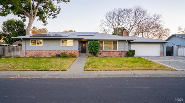 view of front of home featuring a garage, a front yard, and solar panels