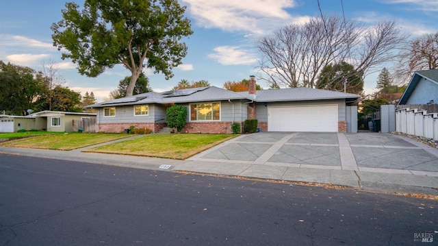 ranch-style house featuring a garage, a front lawn, and solar panels