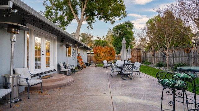 view of patio with french doors, outdoor dining area, and a fenced backyard