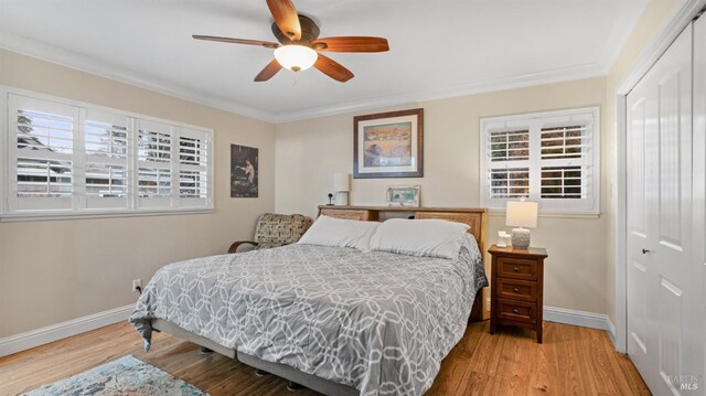 bedroom with wood-type flooring, crown molding, ceiling fan, and a closet