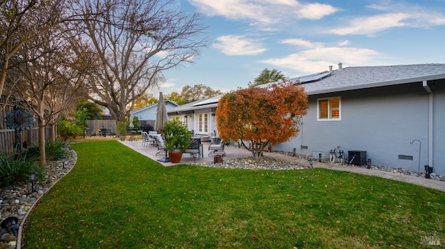 rear view of property featuring fence, crawl space, a lawn, roof mounted solar panels, and a patio area