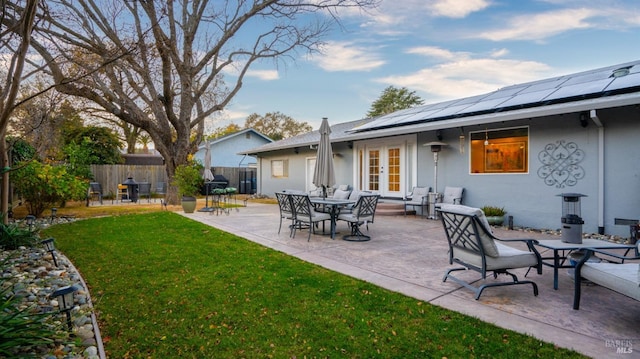 exterior space with fence, a yard, french doors, roof mounted solar panels, and stucco siding