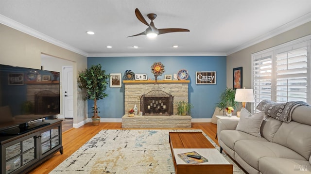 living area featuring crown molding, light wood-type flooring, a fireplace, and baseboards