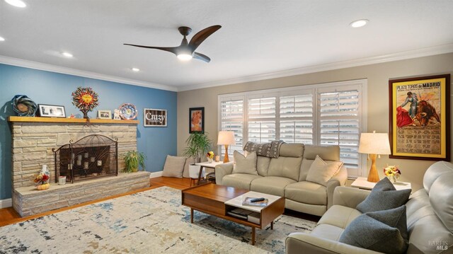 living room with ornamental molding, a stone fireplace, and hardwood / wood-style floors