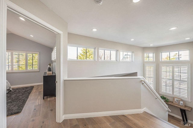 corridor featuring light hardwood / wood-style floors and lofted ceiling