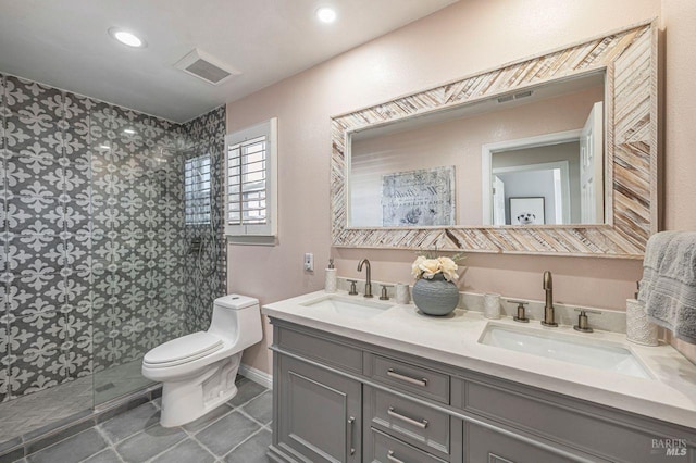 bathroom featuring a tile shower, vanity, and toilet