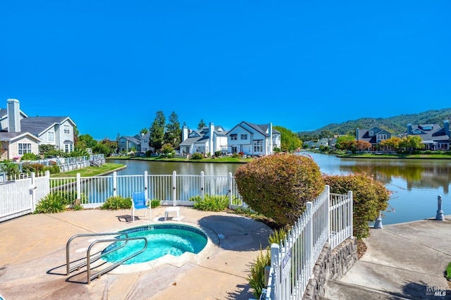 view of pool featuring a patio, an in ground hot tub, and a water view