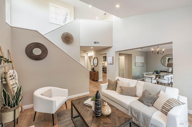 living room featuring an inviting chandelier, a towering ceiling, and wood-type flooring