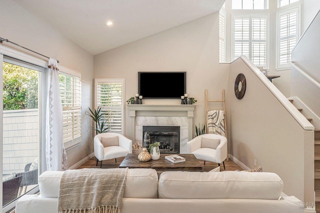 living room with vaulted ceiling, a high end fireplace, and hardwood / wood-style flooring