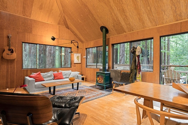 interior space featuring wood ceiling, vaulted ceiling, wooden walls, hardwood / wood-style flooring, and a wood stove