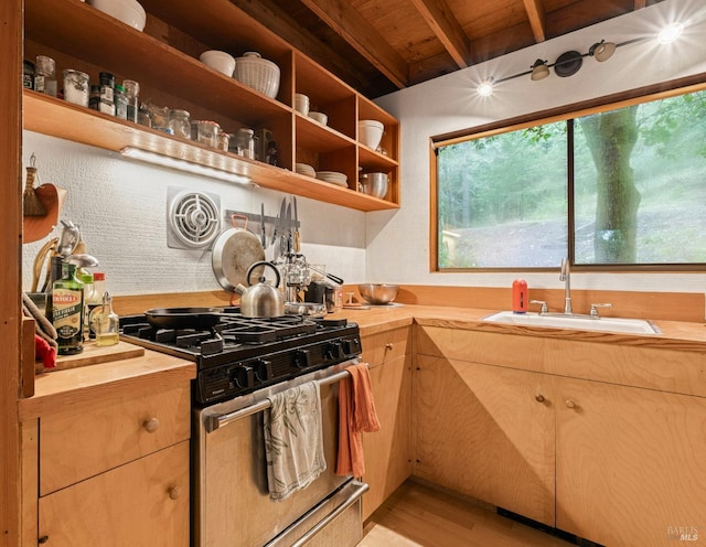 kitchen with gas stove, sink, light hardwood / wood-style flooring, and butcher block countertops