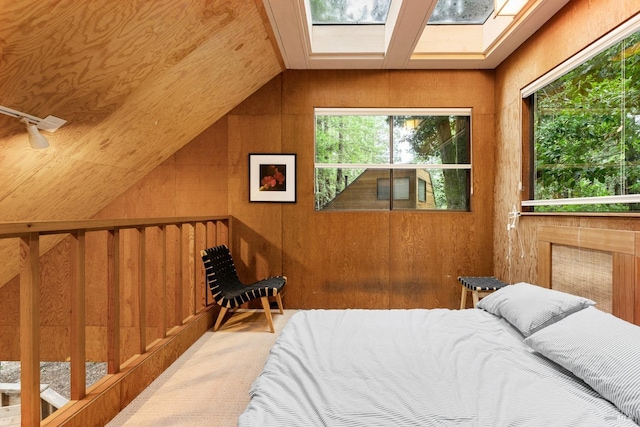 bedroom with wooden walls, carpet floors, wood ceiling, and lofted ceiling with skylight