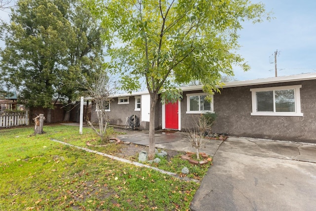 ranch-style home featuring a front yard, a patio, fence, and stucco siding