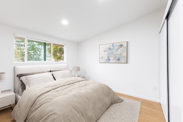 bedroom with vaulted ceiling, recessed lighting, baseboards, and light wood-style floors