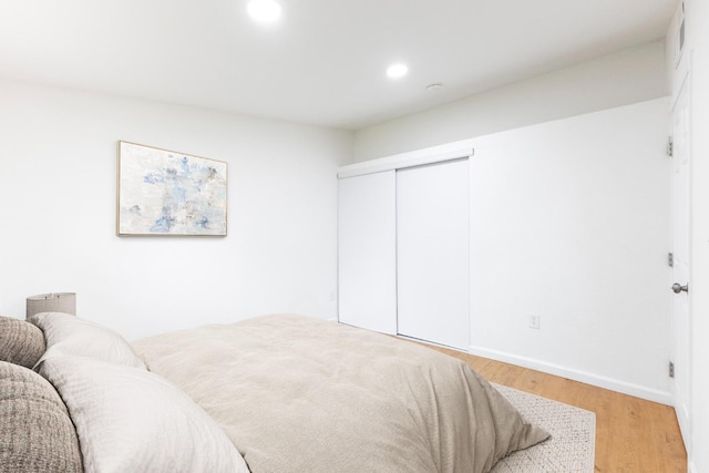 bedroom featuring light wood finished floors, baseboards, a closet, and recessed lighting