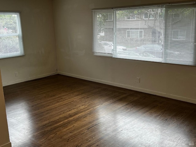 empty room featuring a healthy amount of sunlight and dark wood-type flooring