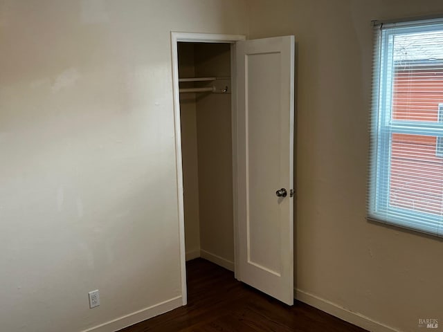 unfurnished bedroom featuring a closet and dark hardwood / wood-style floors