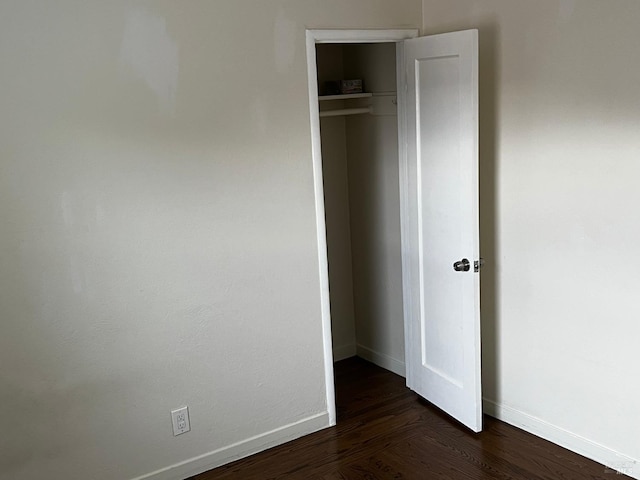 unfurnished bedroom with dark wood-type flooring and a closet