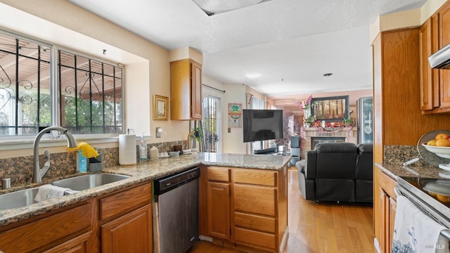 kitchen featuring kitchen peninsula, light stone counters, sink, and stainless steel dishwasher