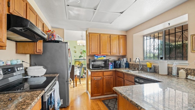 kitchen with stone counters, exhaust hood, sink, light wood-type flooring, and appliances with stainless steel finishes